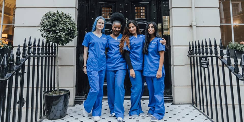 Four nurses in blue scrubs outside a Georgian clinic entrance for EMtone cellulite reduction in Amsterdam