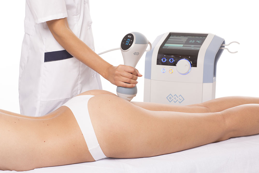 Practitioner treating a woman's thighs with a handheld device, EMtone cellulite reduction Amsterdam